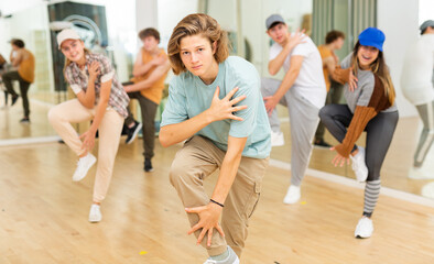 Group of positive teenagers dancing modern dance in ballroom.