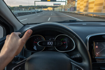 Driver view to the speedometer at 66 kmh or 66 mph on a low traffic road, view from inside a car of...