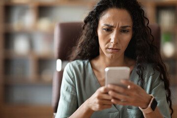 Closeup of confused woman looking at cell phone screen