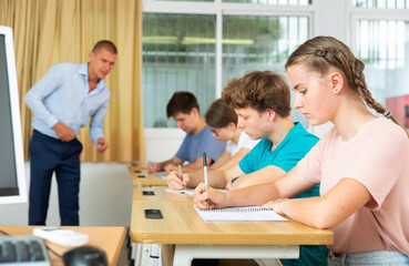 Fototapeta premium Pupils sitting in class and listening carefully to male teacher.