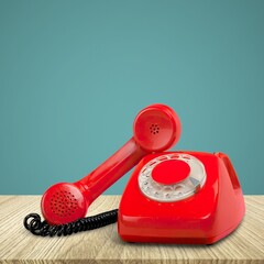 A retro red old telephone on a table.
