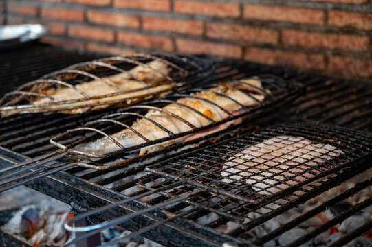 Fresh fish grilling on old charcoal parrillas build outside of buildings in small fisherman's village Getaria, Basque Country, Spain