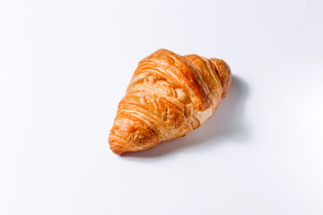 Fresh soft croissant on a white background with space for text. Stylish concept of pastries and breakfasts. Golden French croissant side view