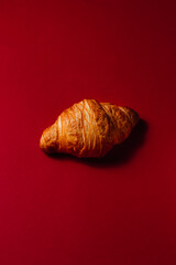 Fresh soft croissant on a red background. Creative concept of pastries and desserts. Stylish French croissant concept with space for text