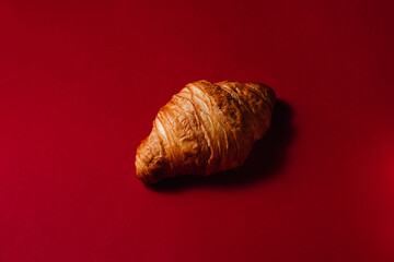 Fresh and soft French croissant on a red background with space for text. Creative concept of delicious pastries for breakfast