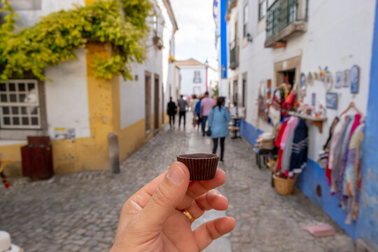 Men hand holding the traditional Ginja de Obidos, traditional sour cherry liquor, served in small cups made of chocolate. Obidos, Portugal