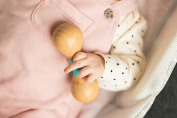 Baby holding a wooden rettle toy