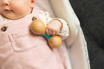 Baby holding a wooden rattle toy