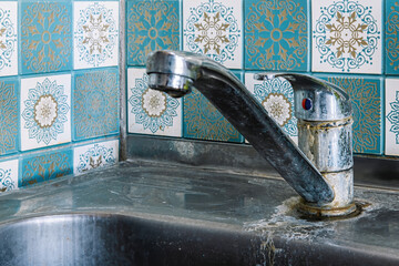 Old rusty sink faucet in kitchen. Rust streaks, calcium scale, hard water.