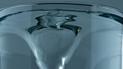 Mineral drink spinning transparent cylinder closeup. Pure water vortex glass