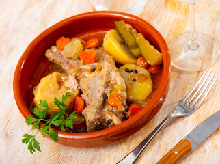 Delicious dish of stewed pork ribs with potatoes and vegetables, decorated with a fresh sprig of greenery