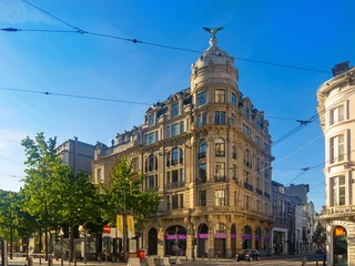 Fotobehang Schilderachtig uitzicht op het zomerse stadsbeeld van Antwerpen met uitzicht op een monumentaal barok kantoorgebouw bekroond met een koepel en een adelaarssculptuur op de hoek van de Meir- en Huidevettersstraat, België. © JackF