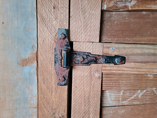 Old wooden door with rusted hinge in a farm house