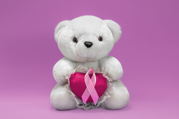White bear with heart and pink ribbon, symbol of pink autumn. Campaign against breast cancer. Pink background, space for writing.