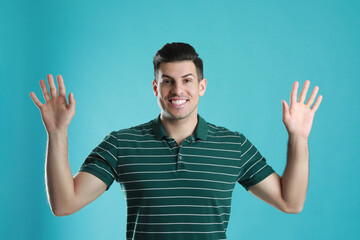 Naklejka premium Cheerful man waving to say hello on turquoise background