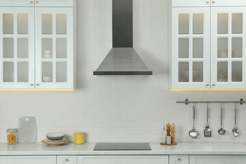Elegant kitchen interior with modern range hood over cooktop and stylish furniture - obrazy, fototapety, plakaty