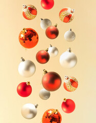 red and silver christmas baubles in fall on bright sand color background. minimal creative new year composition.