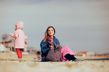 Happy Mother Relaxing at the Beach with her daughter. Little child and its mom enjoying a carefree vacation at the seaside
