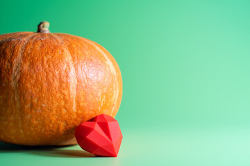 A red heart and pumpkin on green background,copy space