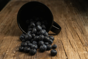 cup of blueberries on wood with dark background