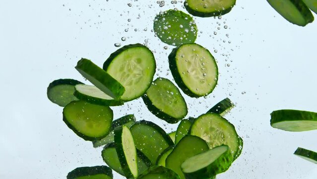 Slices green cucumber floating in water close up. Vegetable raising up in liquid