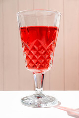 Glass of an exquisite red cocktail on a white surface.