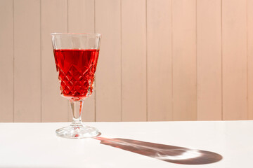 Glass of an exquisite red cocktail on a white surface. Normal view, horizontal orientation. Copy space.