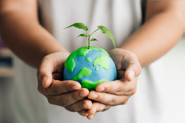 human hand holding young earth and plant in ecology and environment sustainable concept. Saving...