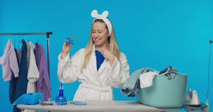 Smiling woman shopping online with credit card while cleaning in the morning ironing doing household