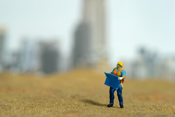 Miniature people toy figure photography. Site visit concept. A construction worker holding...