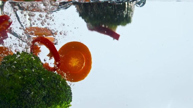 Fresh vegetable fall water in super slow motion close up. Veggies underwater.