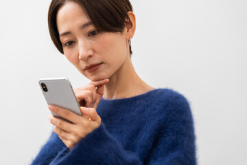 携帯を見て悩むショートヘアーの日本人女性
