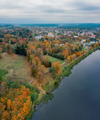 Fototapeta na wymiar Autumn colors in town, nature colored trees beside river and town