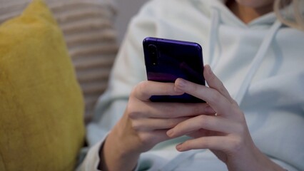 Young female customer using mobile phone while sitting on sofa at home.