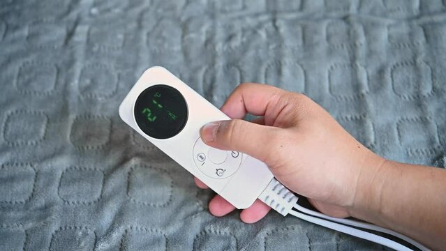 man operating a controller of an electric blanket