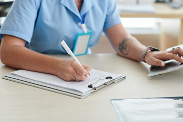 Doctor filling patient card at hospital