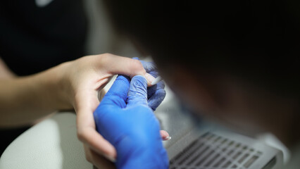 Manicurist specialist in gloves doing hardware manicure to client using special equipment