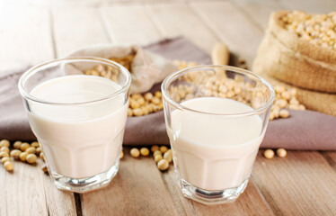 Soy milk in a glass with soybeans on a wooden table organic drink high protein healthy breakfast agricultural produce vegetarian - top view