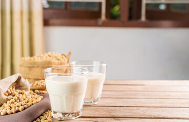 Soy milk in a glass with soybeans on a wooden table organic drink high protein healthy breakfast agricultural produce vegetarian - top view