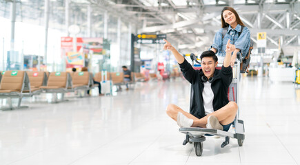 Happy smiling asian male and female waiting for flight and Check-in by mobile phone in terminal background.asian couple are traveling after the coronavirus 2019 (COVID-19) outbreak ends.