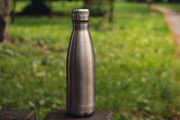Water bottle. Reusable steel thermo water bottle on green grass. Sustainable lifestyle. Plastic...