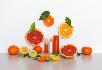 Anti-aging vitamin cosmetics with citrus fruit extracts on wooden podium. Hygienic lipstick, facial serum and shampoo. Around sliced pieces of juicy ripe citrus. Concept of natural cosmetic products