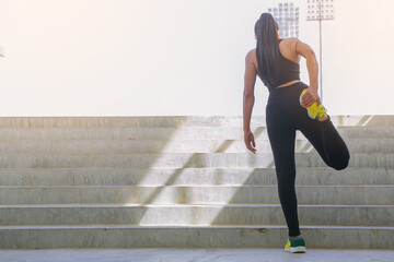 Young woman warming up at the stairway. Fit runner strstching her muscle before workout at stadium stairway. Selected focus