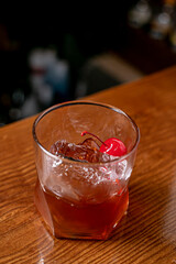 Old-fashioned drink at bar with a slice of orange, cherry and ice, a classic alcoholic drink