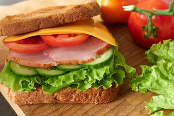 Fototapeta na wymiar Sandwich with meat, cheese slices and juicy vegetables. Concept - appetizing food, restaurant dishes.