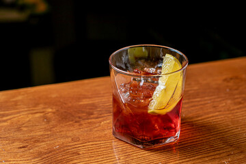 Old-fashioned drink at bar with a slice of orange, cherry and ice, a classic alcoholic drink