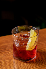 Old-fashioned drink at bar with a slice of orange, cherry and ice, a classic alcoholic drink