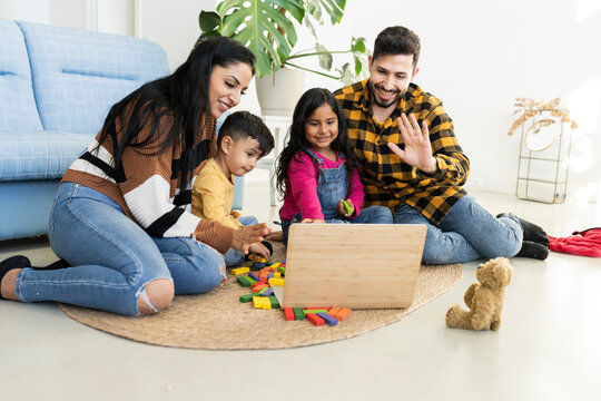 Cheerful Young Indian Family With Kids Laughing Watching Funny Videos On Smartphone Sitting On Sofa Together, Parents With Kids Enjoying Games 