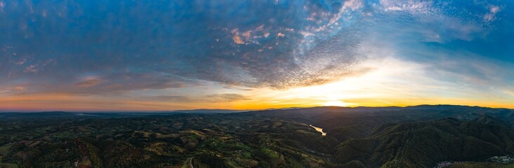 Fototapeta na wymiar Aerial panorama view of a colorful sunrise in a hilly area near Resita city, Romania. Captured with a drone