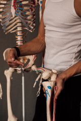 A man holds a skeleton leg in his hands and points a finger at it